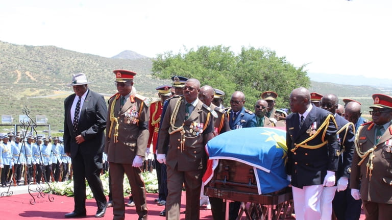 Pallbearers carry the flag-draped coffin of the late Namibian President...