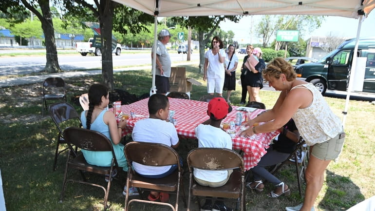 Volunteer Deborah Masotti-Burns assists children having lunch at an LI Cares...