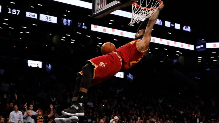 Cleveland Cavaliers forward LeBron James holds onto the rim in...