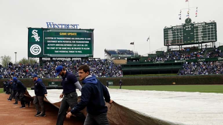 The grounds crew covers the field with a tarp during...