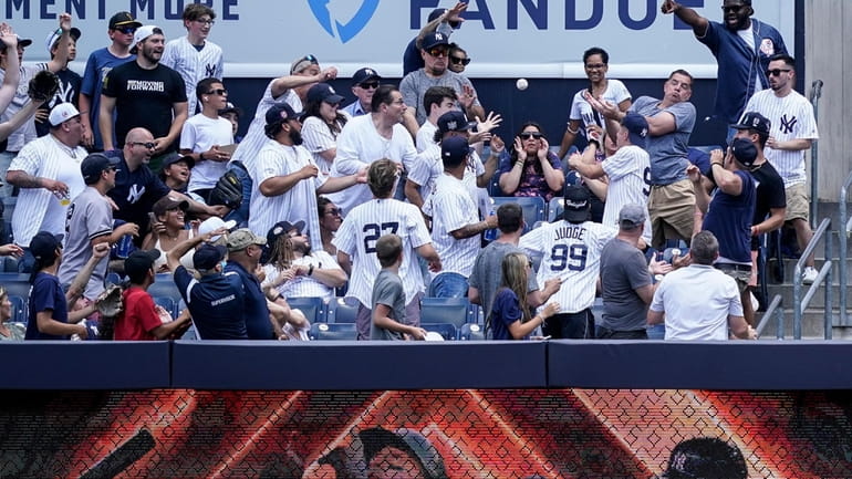 Fans reach for a home run ball hit by New...