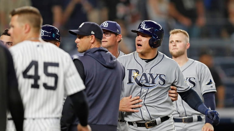 Tampa Bay Rays pitching coach Kyle Snyder, center rear, restrains...