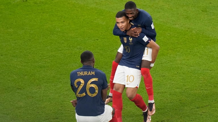 France's Kylian Mbappe, center, celebrates after scoring with teammate France's...