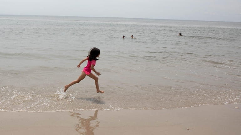 A girl runs along the shoreline at Jacob Riis Park in...