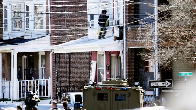 Police surround a home in Trenton, N.J., Saturday, March 16,...