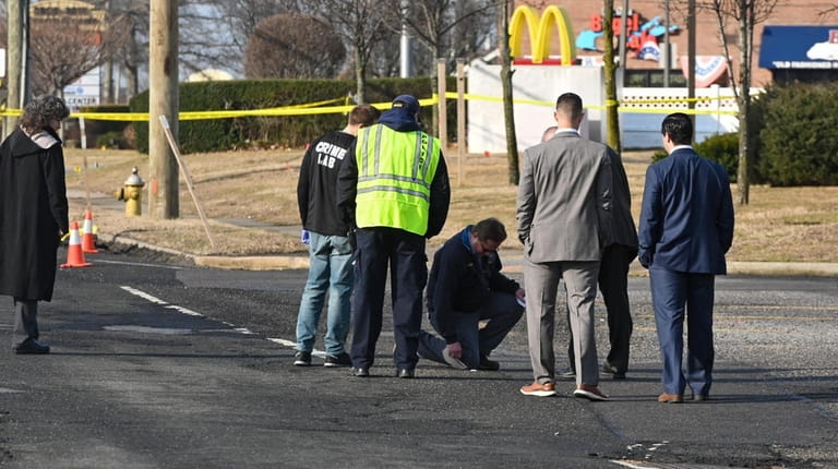 Investigators at the scene of a fatal hit-and-run incident that...