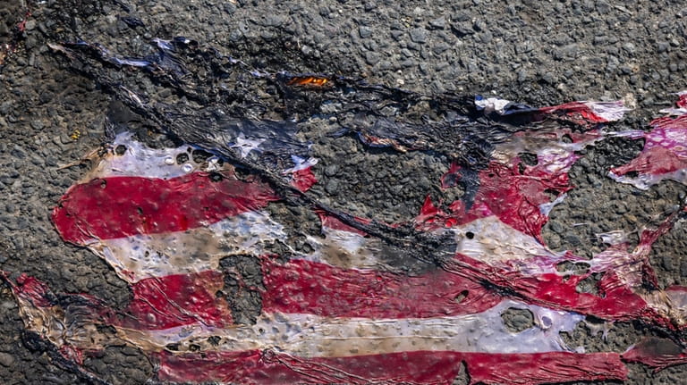 What remains of a U.S. flag covers the street after...