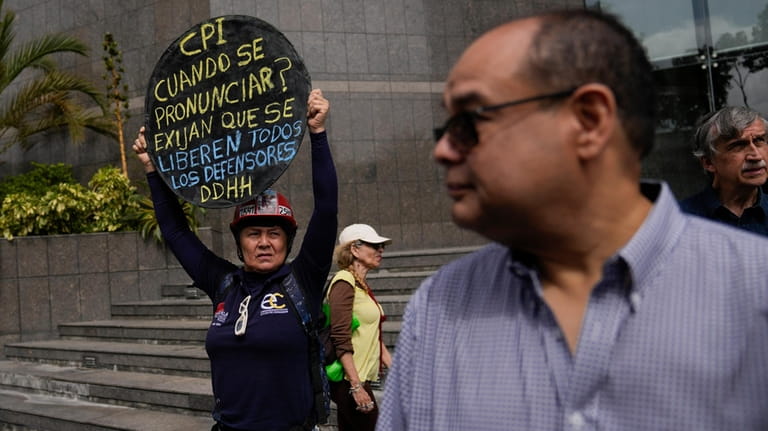 A protester holds up a sign that reads in Spanish...