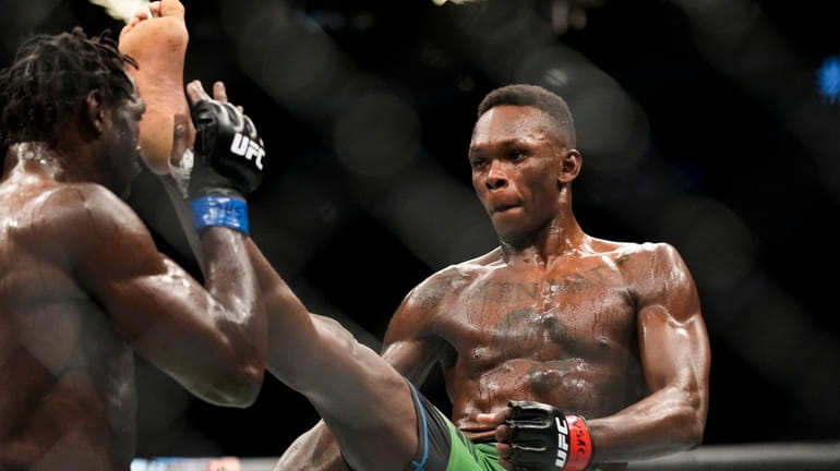 Israel Adesanya, right, kicks Jared Cannonier in a middleweight title...