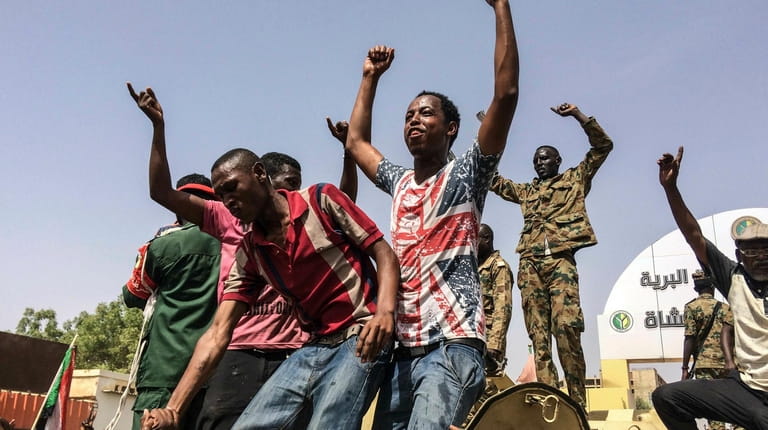 Sudanese celebrate after officials said the military had forced longtime...