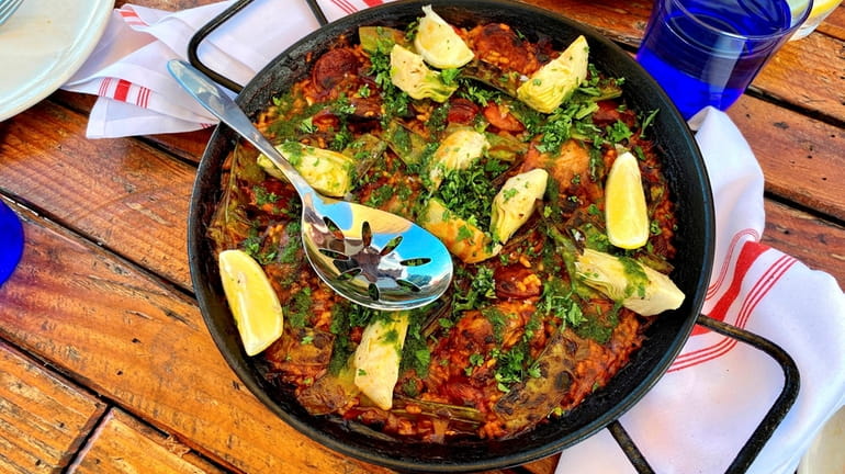 Paella campesina, topped with chicken, chorizo sausage and artichokes, is...