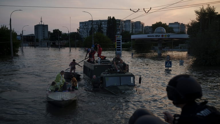 Residents are evacuated from a flooded neighborhood in Kherson, Ukraine,...