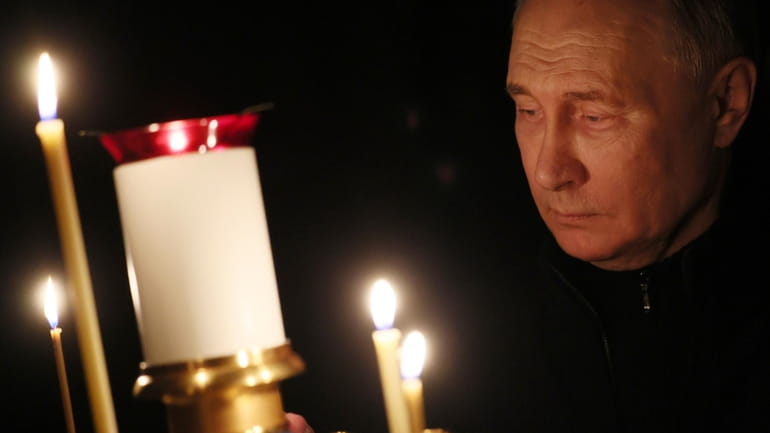 Russian President Vladimir Putin lights a candle to commemorate the...