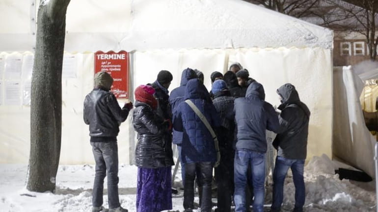 Migrants line up for an appointment in front of a...
