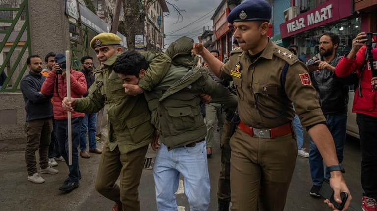 Police officers detain a member of Aam Admi Party, or...