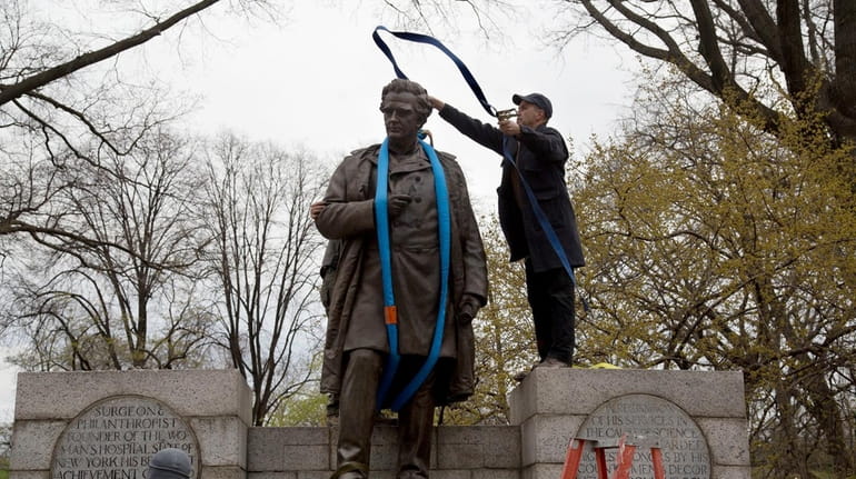 A worker tosses a strap over the 19th century statue...