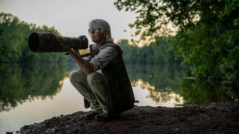 Nature photographer and author Vicki Jauron crouches to take a...