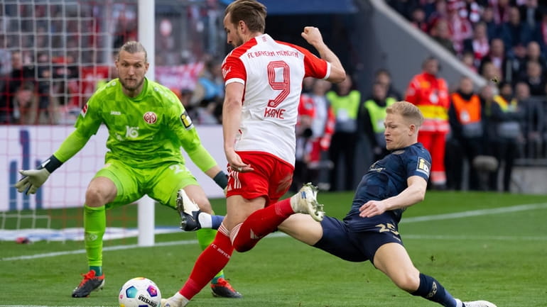 Munich's Harry Kane, center, vies for the ball with Mainz's...