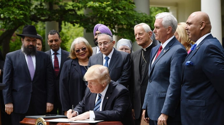 Flanked by Vice President Mike Pence and religious leaders, President...