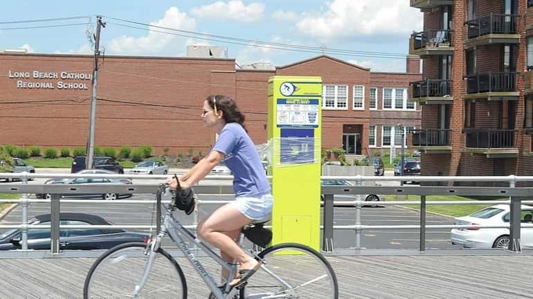 Bicyclists pass the the Decobike bicycle kiosk on the western...