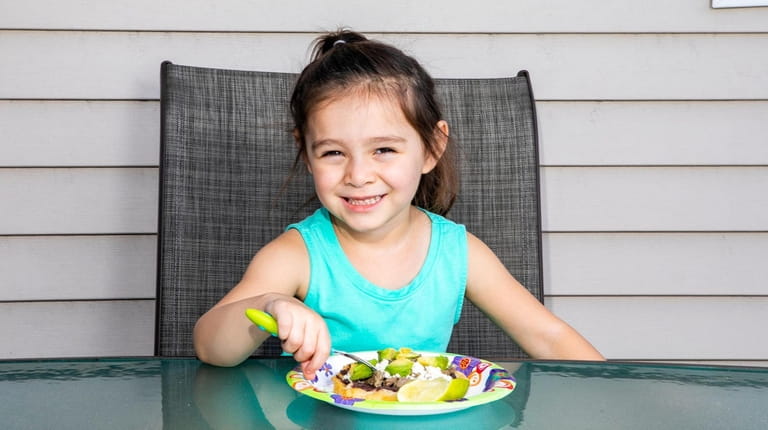 Naomi Romero, 4, with a plate of sopes at home in...