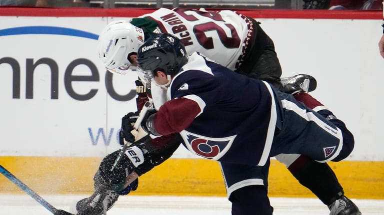 Colorado Avalanche center Evan Rodrigues, front, fights for control of...