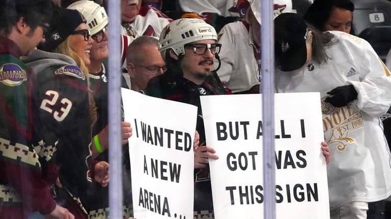 Arizona Coyotes fans hold up signs during the second period...