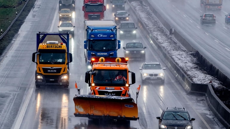 A salt truck drives on the highway as rain sets...