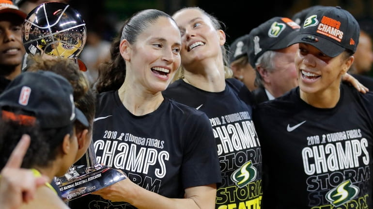 Storm guard Sue Bird, left, holds the championship trophy with...