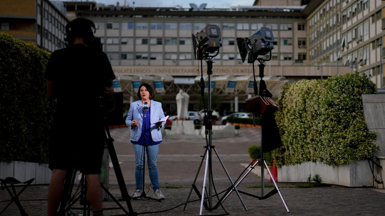 A video journalist talks to camera in front of the...