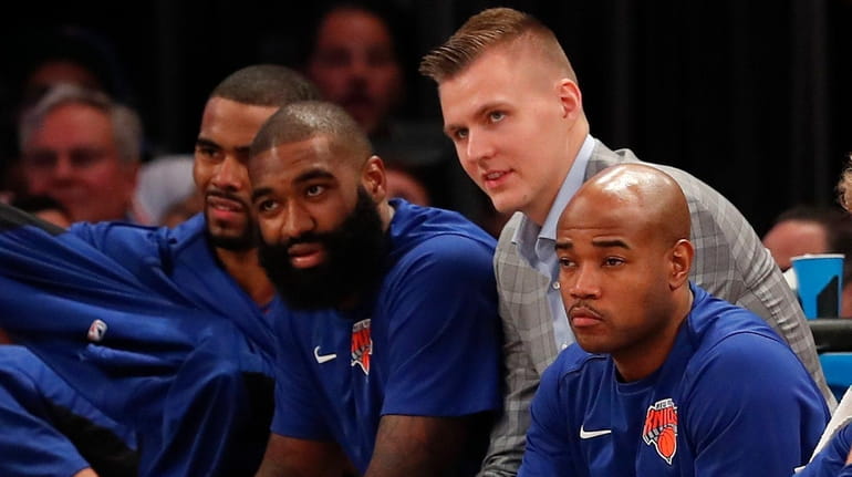 Knicks forward Kristaps Porzingis, center, watches play from the bench...