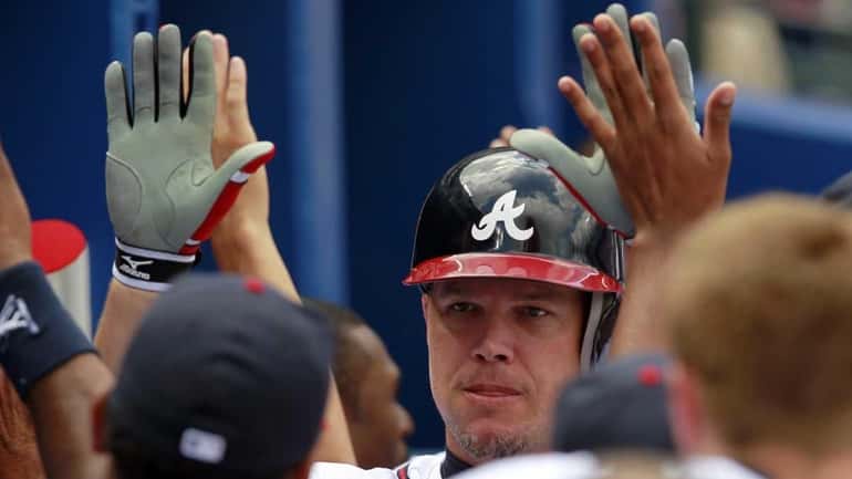 Atlanta Braves' Chipper Jones is greeted in the dugout after...