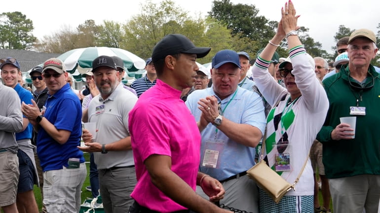 Spectators cheer as Tiger Woods heads to the first tee...