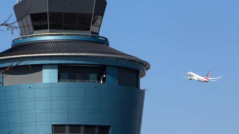 A plane passes the air traffic control tower at LaGuardia...