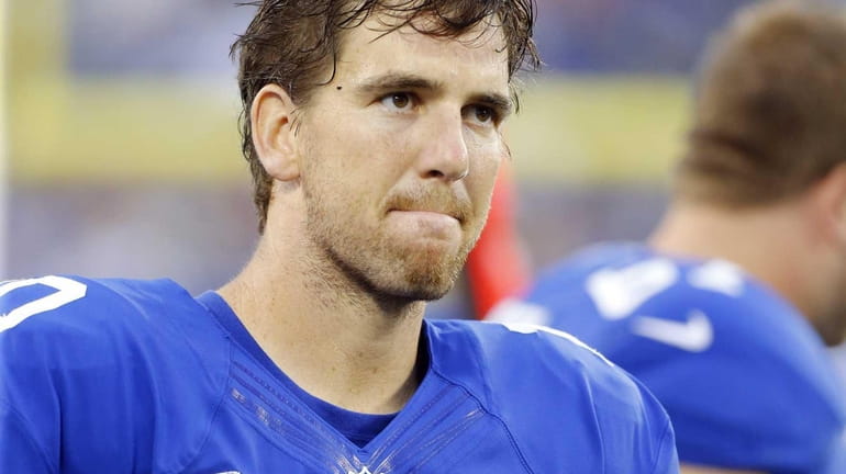Eli Manning looks on from the sidelines after throwing an...