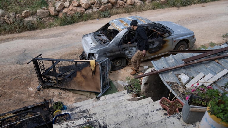 Mohammad Bader, 27, inspects his torched vehicle, in the West...