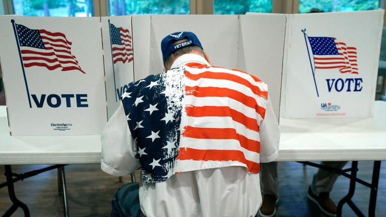 A patriotic voter sits at a voting kiosk and selects...