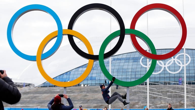 A participant hangs from the Olympic rings while posing for...