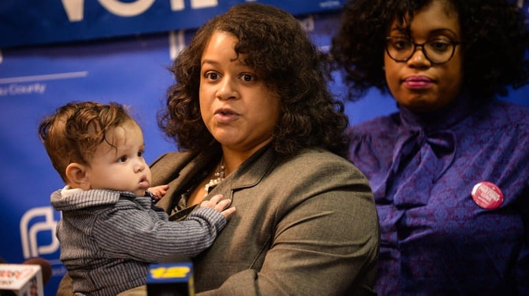 Assemb. Michaelle Solages speaks in Hempstead while holding her son,...