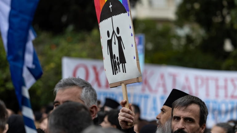 A protester raises a banner during a rally against same-sex...