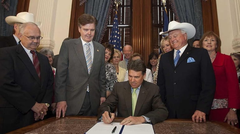 Texas Gov. Rick Perry is flanked by state senators and...