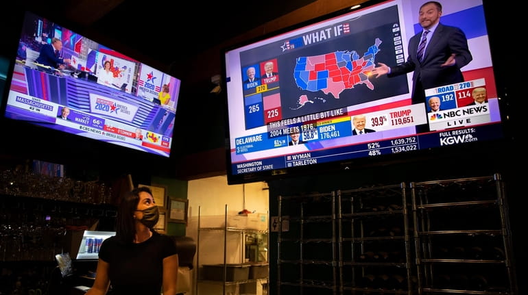 Bartender Sam Schilke watches election results on television at a...