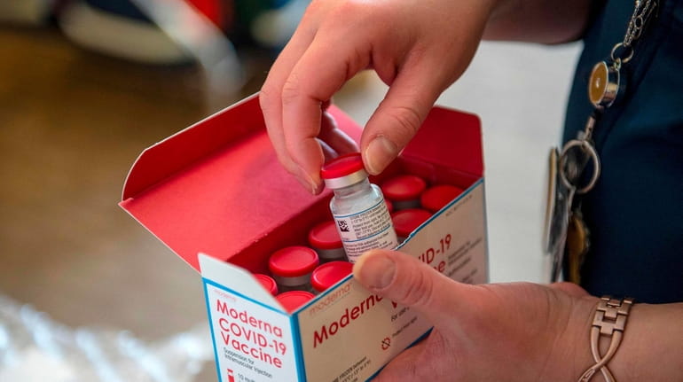 A nursse unpacks a refrigerated box of Moderna COVID-19 vaccines...