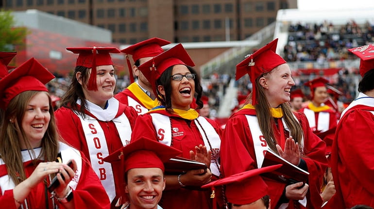 Graduates react to their school being recognized during commencement at...