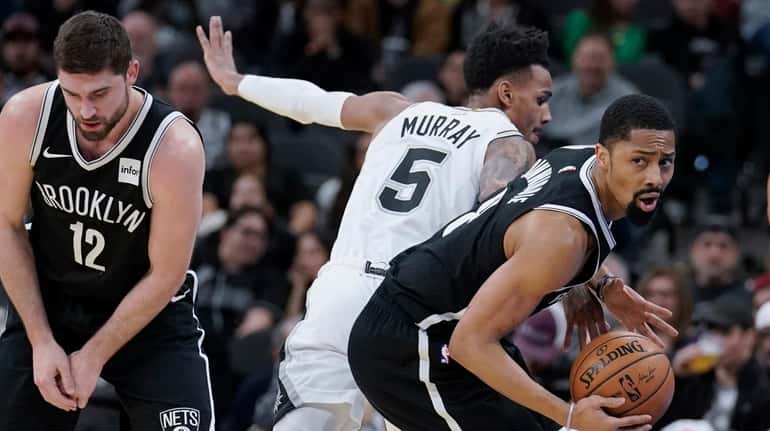 Nets' Spencer Dinwiddie, right, gets away from San Antonio Spurs'...