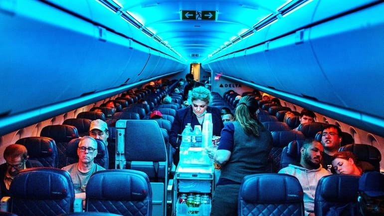 Flight attendants serve refreshments on a Delta Airlines flight from...