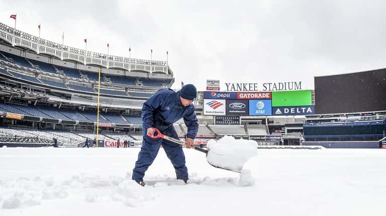 Members of the grounds crew at Yankee Stadium work to...
