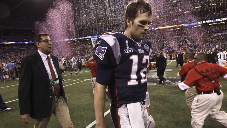 New England Patriots quarterback Tom Brady walks off the field...