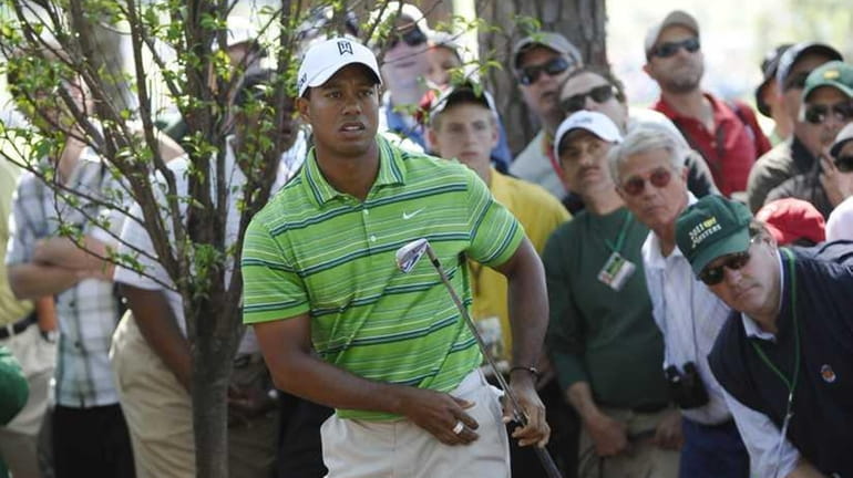 Tiger Woods watches after taking a shot from near a...