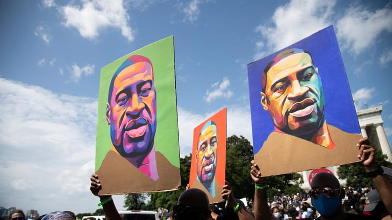 Protesters carry portraits of George Floyd, as thousands march after...